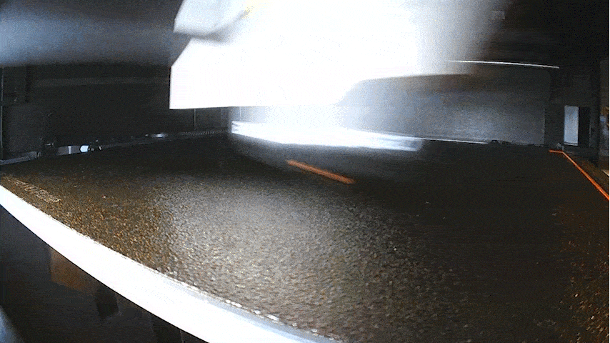 Time-lapse video from inside the 3D printer, showing a circular orange disc being printed