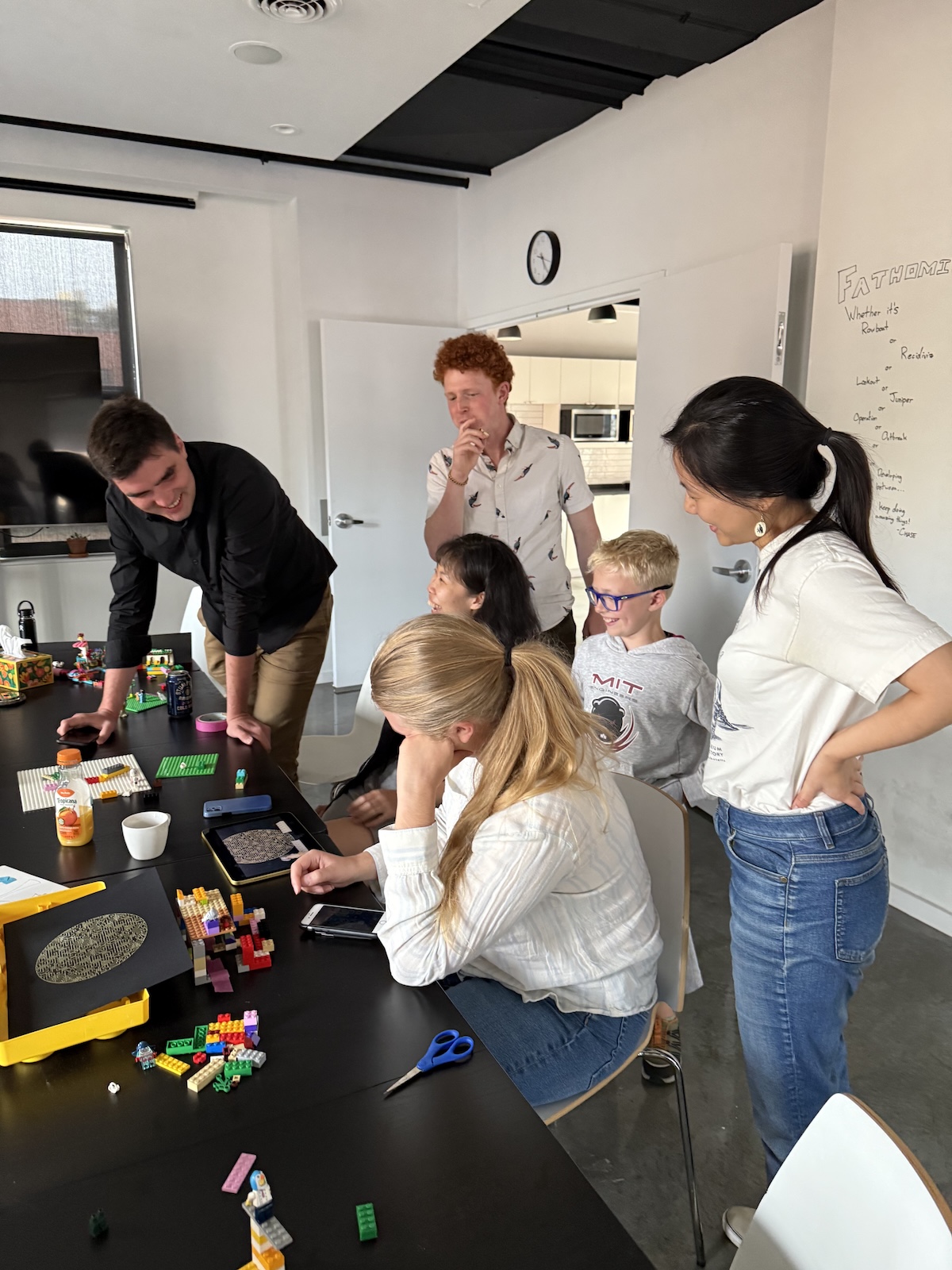 A group of people gathered around an iPad and Legos